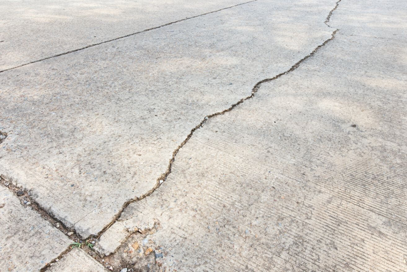 Large crack running across a concrete driveway — sunken or uneven slab